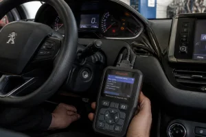 Voyant service allumé sur le tableau de bord d'une Peugeot 208 avec lecteur OBD2 branché